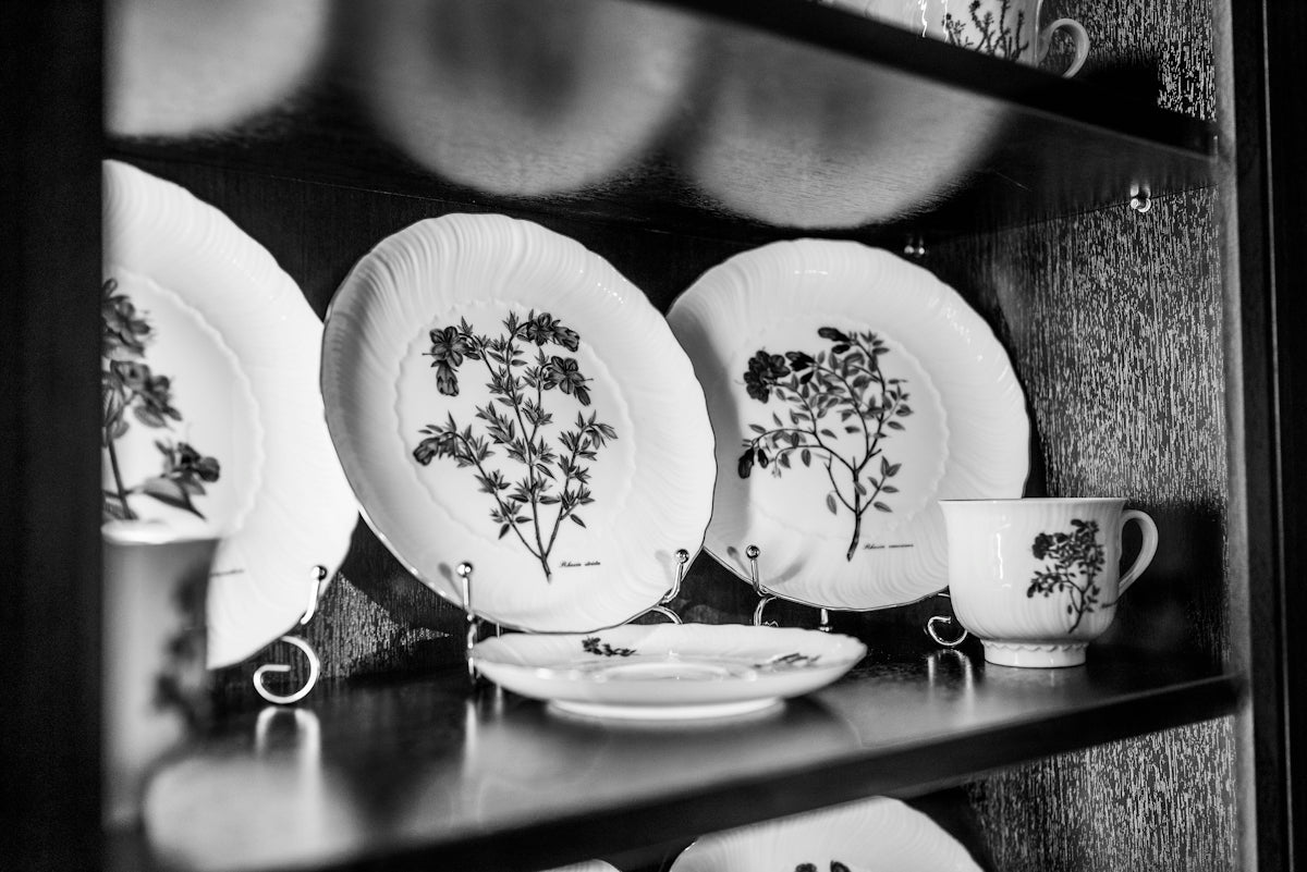Decorative plates and teacup with floral designs displayed on shelf